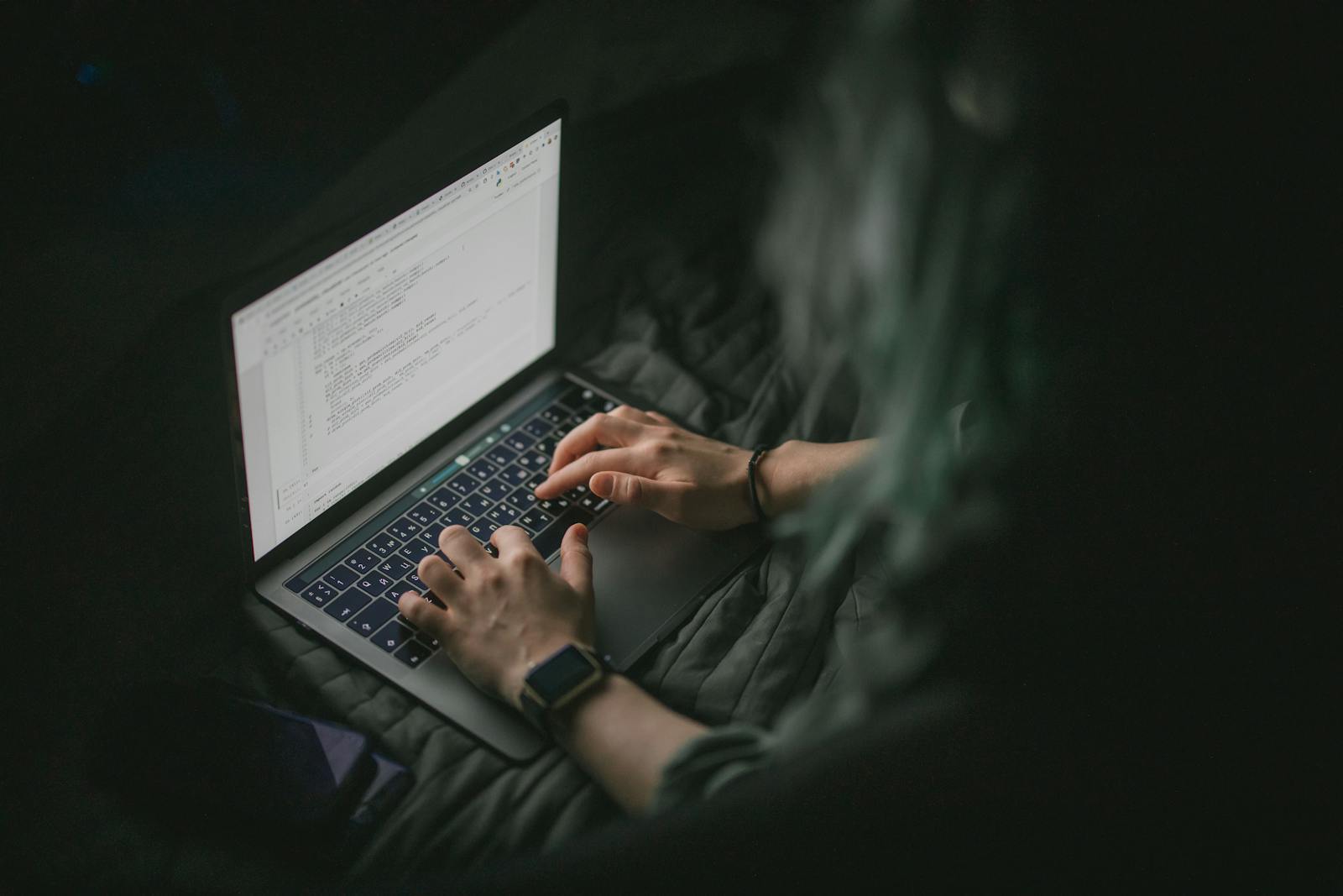 Close-up of hands typing on a laptop with code on screen, perfect for work from home and tech themes.
