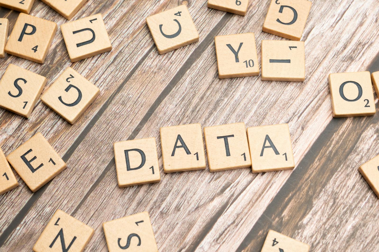 Wooden letter tiles spelling 'DATA' on a wood textured surface, symbolizing data concepts.