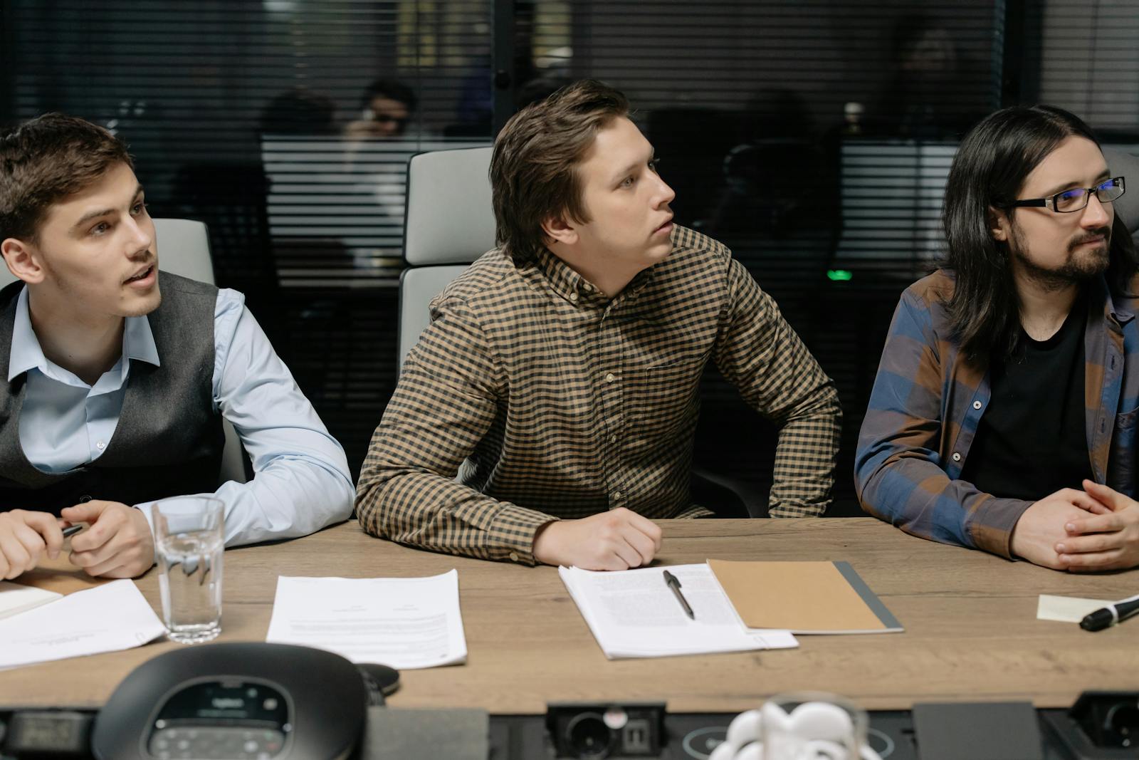 Three men engaged in a business meeting, focusing on a presentation.