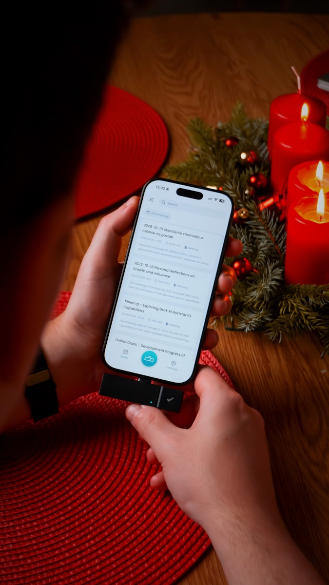 Person holding smartphone near christmas candles